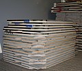 Stacks of plywood-backed billiard table bed slates. The cheaper, darker ones on top are noticeably thinner than the higher-quality light grey ones. (Alternate view.)