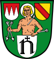 Gemeinde Steinfeld In Grün aus einem silbernen Schild, darin der mit einem schwarzen Kreuzchen überhöhte unziale Großbuchstabe N, wachsend der silbern nimbierte heilige Sebastian, der in der Rechten zwei gestürzte schräg gekreuzte silberne Pfeile hält, beseitet oben rechts von einem roten Schild mit drei gesenkten silbernen Spitzen, oben links von einem goldenen Schild mit roten Schrägbalken.