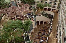 A vast hotel atrium showing a raised platform and large trees.