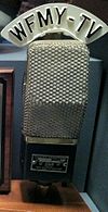 An old microphone with a custom W F M Y - TV label on the top