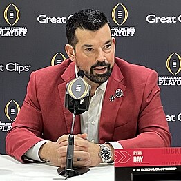 A football coach speaks in front of a microphone.