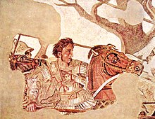 A young man in heavy armour on a horse. He wears a breastplate with Medusa on it, has wavy dark hair, and a determined look on his face.