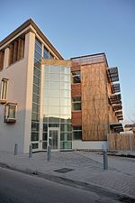 tall, thin, modern building finished in much wood and glass on a sunny day against a blue sky