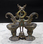 Bronze bird with ring in its beak and two cups