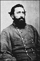 Black and white photo of a heavy-set, dark-haired and bearded man. He wears a gray military uniform with two rows of buttons.