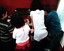 A group of Pre-K children huddle around a cage of the classroom pet.