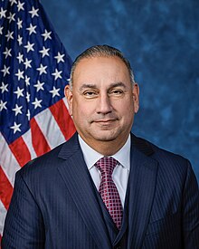 Official House portrait of Cisneros in front of the U.S. flag, wearing a black suit, white shirt, and checkered red tie.