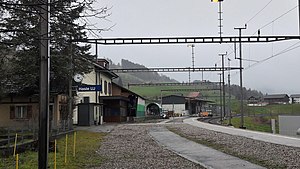 Single-story building next to platform and single-tracked railway line