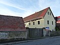 Bauernhof mit Wohnstallhaus, winkelförmig angebauter Scheune, Seitengebäude entlang der Straße (Querbau) und Hofeinfahrt