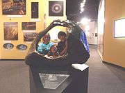 Children posing behind the Tucson Meteorite on exhibit in the “Origins Hall”