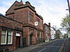 A two-storey building in sandstone with an arched doorway, and mullioned and transomed windows