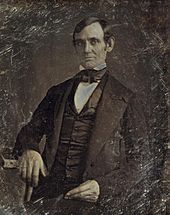 Middle aged clean shaven Lincoln from the hips up.