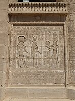 Relief auf einer Stellwand zwischen Säulen in Dendera, mit Abbildungen von Sumpfpflanzen am Sockel, Torusleisten, die das Relief einrahmen, und einem Hohlkehlgesims mit einem Flügelsonnesemblem, das von einem Fries aus Uräen gekrönt wird. Erstes bis zweites Jahrhundert n. Chr.[159]