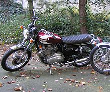 Red-and-white motorcycle, parked on fallen leaves