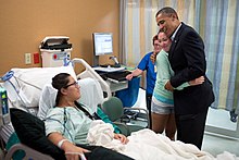 Photo of Obama smiling at a hospital patient while hugging her friend