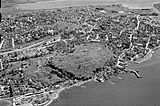 Slottsfjellet, landemerket i byen, med jernbanestasjonen et stykke bak. Flyfoto fra 1957. Foto: Widerøe/Vestfoldmuseene