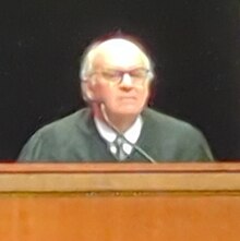 Justice Hill sitting at a dais