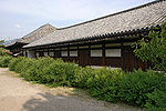 Long wooden building with white walls.