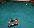 Racking up a game of three-ball, in straight line formation, using the diamond rack more commonly used for nine-ball, but at an angle so that side is perfectly aligns the balls with the center diamonds on the head rail and foot rail. In this example, the 2 ball is on the foot spot. (Cropped version.)