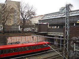 Een S-Bahntrein richting Ostkreuz kruist de Schönhauser Allee onderlangs voor het bereiken van het station; op de achtergrond het luchtspoorstation van de metro.