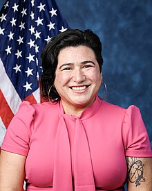 Official House portrait of Randall smiling in front of the U.S. flag, wearing a pink shirt.