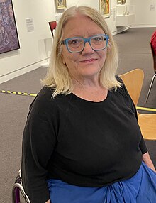 Photo of female paralympian seated with art works in background