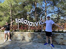 A Sign from the Village of Vavatsinia. 2 Tourist children are next to it.