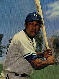 A man in a white baseball uniform and blue hat