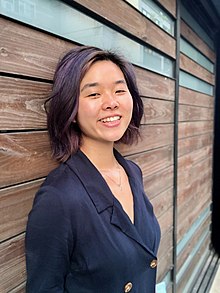 Laura Gao standing in front of a wooden background