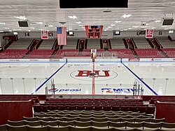 A view of the ice surface of Walter Brown Arena from the Away bench side. The ice surface is clean and there are no spectators or players.