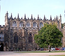 A two to three-storey high stone building. The building is topped with castellations and pinnacles