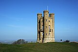 Golden limestone tower with three circular turrets that run the height of the building.