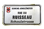 Zweisprachiges Schild in Junglinster: Schoulstrooss / Rue du Ruisseau (franz. für Bachstraße)