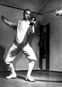 Edoardo Mangiarotti in a fencing pose with a rapier and no mask on.