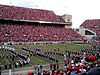 An image of a packed college football stadium taken from a couple dozen rows up showing the Ohio State marching band in the script OHIO formation.