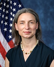 Official House portrait of Dexter in front of the U.S. flag, wearing a black shirt and multi-colored bead necklace.