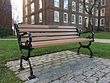 Photo of a memorial bench installed in grass field on the side of a path.