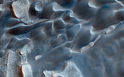 Closeup, color-enhanced image of Olympia Undae dunes with melting/subliming ice-cap fragments. Note Barchan dunes and patterned ground. Width of image is about 1 km/3000 ft.