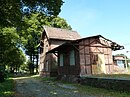 Bahnhof Buckow, bestehend aus Empfangsgebäude mit Güterschuppen und gepflasterter Lindenallee