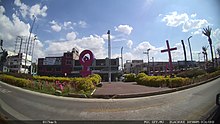 alt:A park with the sculpture of a symbol of Venus surrounded by several crosses.