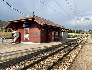 Brown station building with a ticket machine next to a railway line