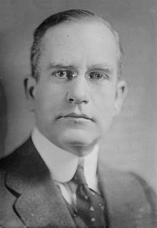 Black and white portrait photograph of Shaw from neck up wearing a suit jacket, necktie, and glasses