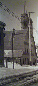 Black and white image of exterior of arena along a downtown street