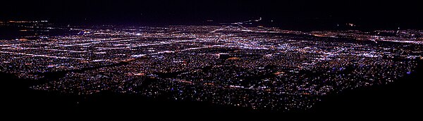 Photo shows the nighttime cityscape of Albuquerque as seen looking west by south from the upper terminal of Sandia Peak Tramway