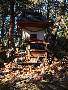 A small structure with a number of cat figurines in front of it