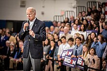 Photo of Biden holding a microphone, with a crowd in the background