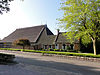 Kop-hals-rompboerderij met voorhuis met zesruitsvensters, kleine lichtopeningen en schoorstenen waarop borden