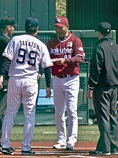 Man wearing a baseball uniform walking onto the field.