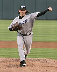 A man in a gray baseball uniform and black undersleeves and cap