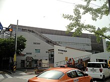 A large grey building with Korean text on the front, and an external staircase going upwards from right to left halfway up the building